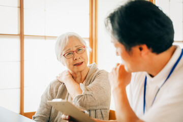 在宅介護を受ける高齢者女性（肩こり）
