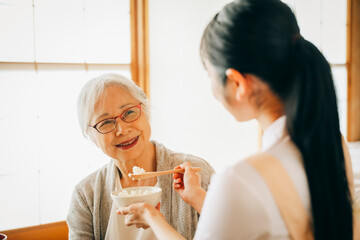 食事をする高齢者女性と女性スタッフ（食事介助）
