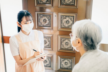 高齢者住宅に訪問する女性（書類・マスク）
