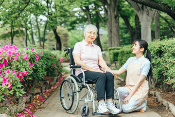 Obraz na płótnie Canvas 車椅子に乗った高齢者女性と女性スタッフ 