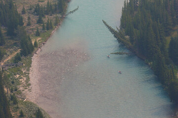Two kayakers gliding down the Bow River just outside of Banff, Alberta.  Shot from high over head.