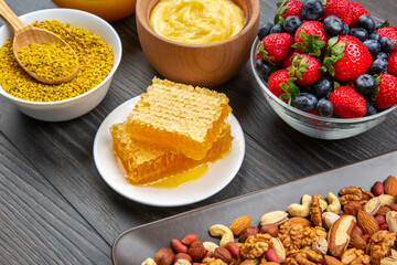 fresh assorted honey, nuts, strawberries and blueberries on a wooden background. healthy organic vitamin food.