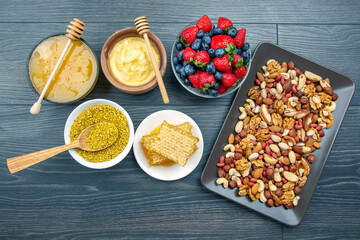 fresh assorted honey, nuts, strawberries and blueberries on a wooden background. healthy organic vitamin food.