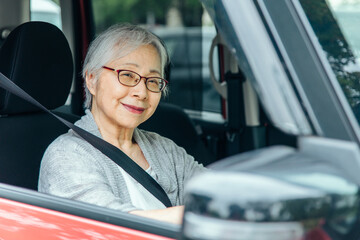自動車の運転をする高齢者女性（笑顔）
