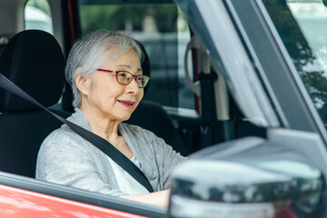 自動車の運転をする高齢者女性（笑顔）
