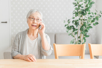 スマホで電話する高齢者女性（笑顔）
