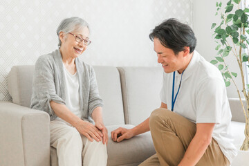 Obraz premium 訪問介護する男性と高齢者（膝） 