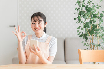 スマホを使うエプロン姿の女性（OK）
