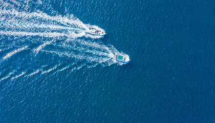 Two boats floating on the sea at high speed drone view.