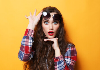 Lifestyle, emotion and people concept: Young surprised woman wearing casual over yellow background
