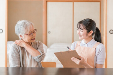 在宅介護を受ける高齢者女性（肩凝り）
