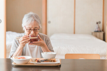 和室で食事を食べる高齢者女性（味噌汁）
