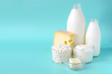 A set of dairy products close-up on a blue background close-up. Milk, kefir, sour cream, cheese, butter and cottage cheese in a glass container on a light background