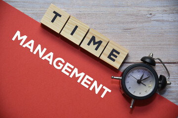 TIME wording on wooden blocks and MANAGEMENT text on red background with analog alarm clock....