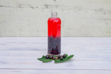 Compote or mors made from black currant berries in a bottle on the table in the garden © Olga