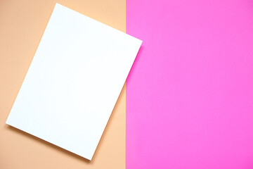 top view of vertical blank white paper card placed on pink paper and old rose color paper background, flat lay.