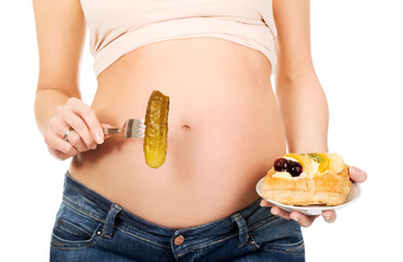 Closeup of a woman with her pregnant belly holding various food