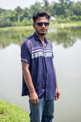 A young boy is standing on the ground wearing a dark blue shirt and black sunglasses with styling and his behind the background blur.