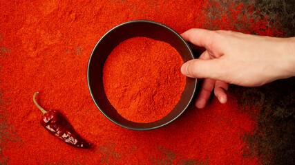 TOP VIEW: Human hand takes a dish with red pepper powder from a table