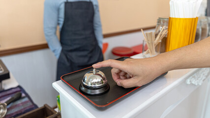 Closeup shot, a hand of customer is ringing the bell at coffee shop counter to call for attention