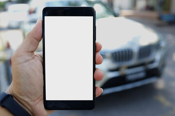 Adult hand holding a smartphone at outdoor with blank copy space screen for text message or information content