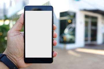 Adult hand holding a smartphone outside a store with blank copy space screen for text message or information content