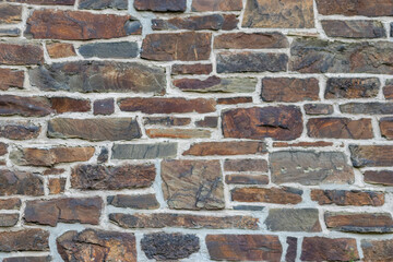 Massive stone wall with rough rocks like a castle wall with different bricks as natural background and rocky wall of ancient times shows solid bricks of stones as vintage texture for granite minerals