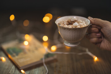 Picture of a coffee cup fill with marshmallow placing on a wooden plate with a clear cup fill with marshmallow along side.