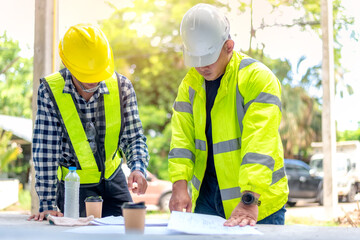 Construction worker, foreman stands and consults the construction plan with the construction site...