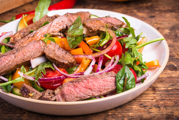 American salad with vegetables and pieces of beef steak, close-up