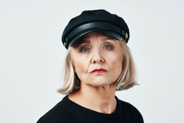 elderly woman in a black hat fashion close-up light background