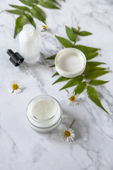 Fototapeta na wymiar Natural cosmetic products. Daily hygiene and female healthy skincare. Cosmetic cream and skin care serum with cammomile flofers on marble countertop. SPA organic beauty product.