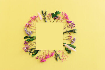 Top view image of pink, purple and green flowers composition over pastel yellow background .Flat lay