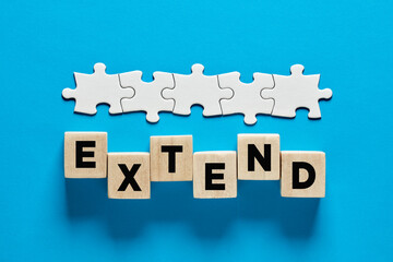 To extend a business contract or time extension. The word extend on wooden cubes.