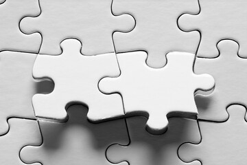 Fototapeta premium Jigsaw puzzle with two connected pieces are about be placed. Puzzle game, solution, connection