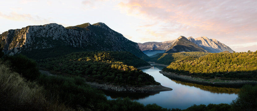 Stunning panoramic view of the Cedrino Lake (Lago del Cedrino) with the mountain range of Supramonte illuminated by a beautiful sunrise. Sardinia, Italy.