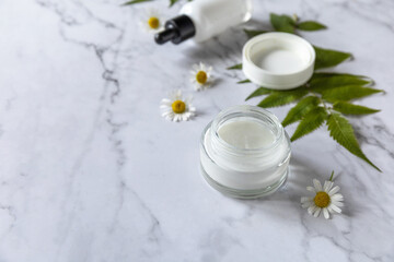 Fototapeta na wymiar Natural cosmetic products. Daily hygiene and female healthy skincare. Cosmetic cream and skin care serum with cammomile flofers on marble countertop. SPA natural organic beauty product. Copy space.