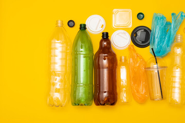 Heap of plastic disposable packaging and disposable tableware on yellow background. Concept of zero pollution and eco-friendly.