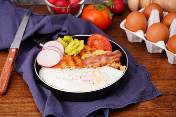 Breakfast bread with fried egg, bacon, pepper, avocado, tomato p