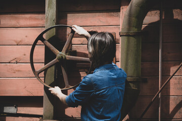 young woman near wheel of an old wooden combine harvester of XIX century