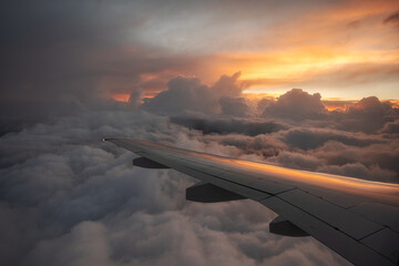 Obraz premium Evening flight over storm clouds. Flight during a storm. View of the beautiful sunset from the plane window.