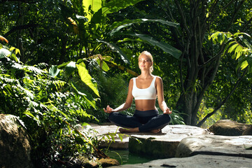 Portrait of young woman practicing yoga in tropic environment - 457654872