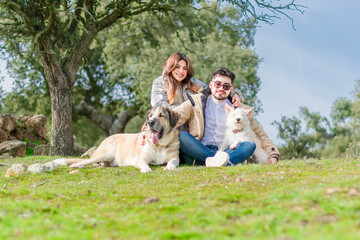 Obraz premium young couple next to an oak tree with two dogs 