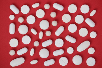 Bright red background with white medicine tablets	