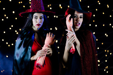 Studio shot of Asian and Caucasian scary fierce sexy female models in black red witch dress costume...
