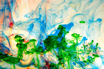 Green, blue and red paint in water on a light background