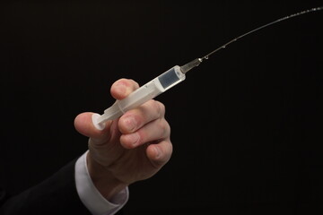 Human hand holding syringe with vaccine on black background