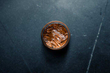 iced coffee in iridescent stemless glass served on black table at cafe​