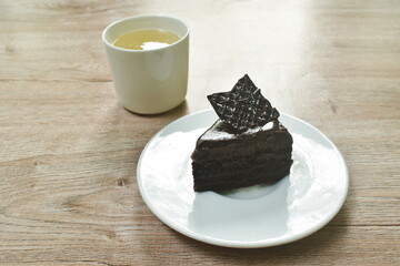 black forest cake with cream topping chocolate and hot tea cup on table