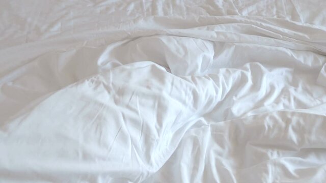 Bedlinen in the morning. Close-up of messy pillow, sheet, blanket on a bed after sleeping, unmade beds after wake up, video 4k resolution